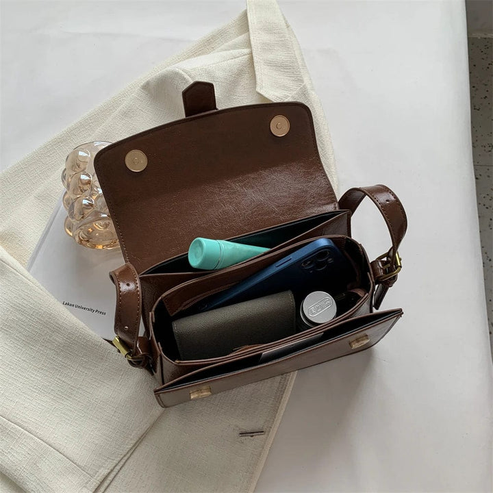 Détail du fermoir doré sur sac besace femme en cuir PU noir, style élégant