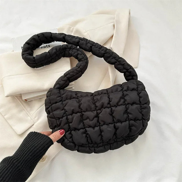Sac besace femme matelassé posé sur une surface, montrant sa forme compacte et légère
