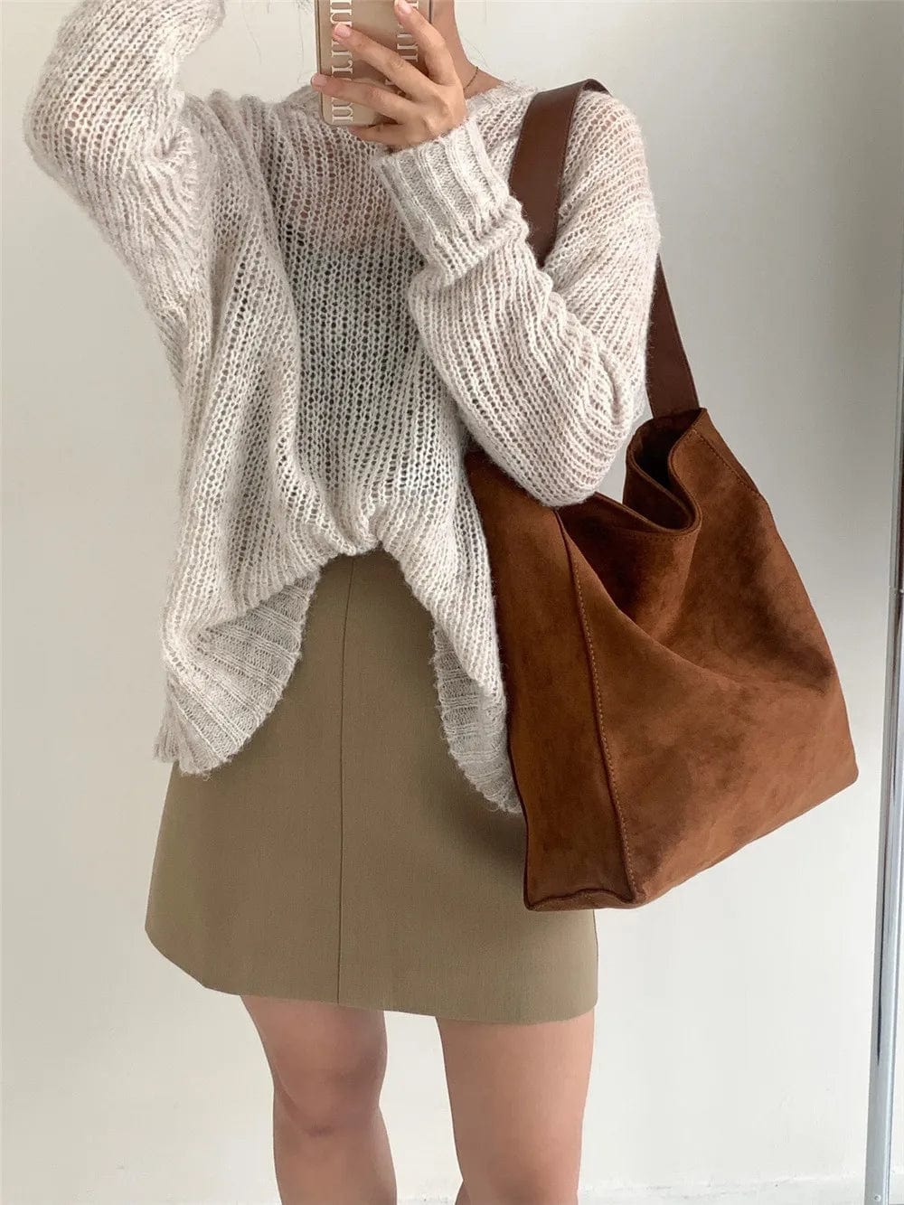 Trois sacs cabas en faux daim (marron, vert, noir) alignés, montrant les variations de couleurs.