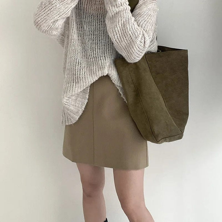 Sac cabas élégant en faux daim vert, posé sur une surface neutre, mettant en valeur sa couleur riche.
