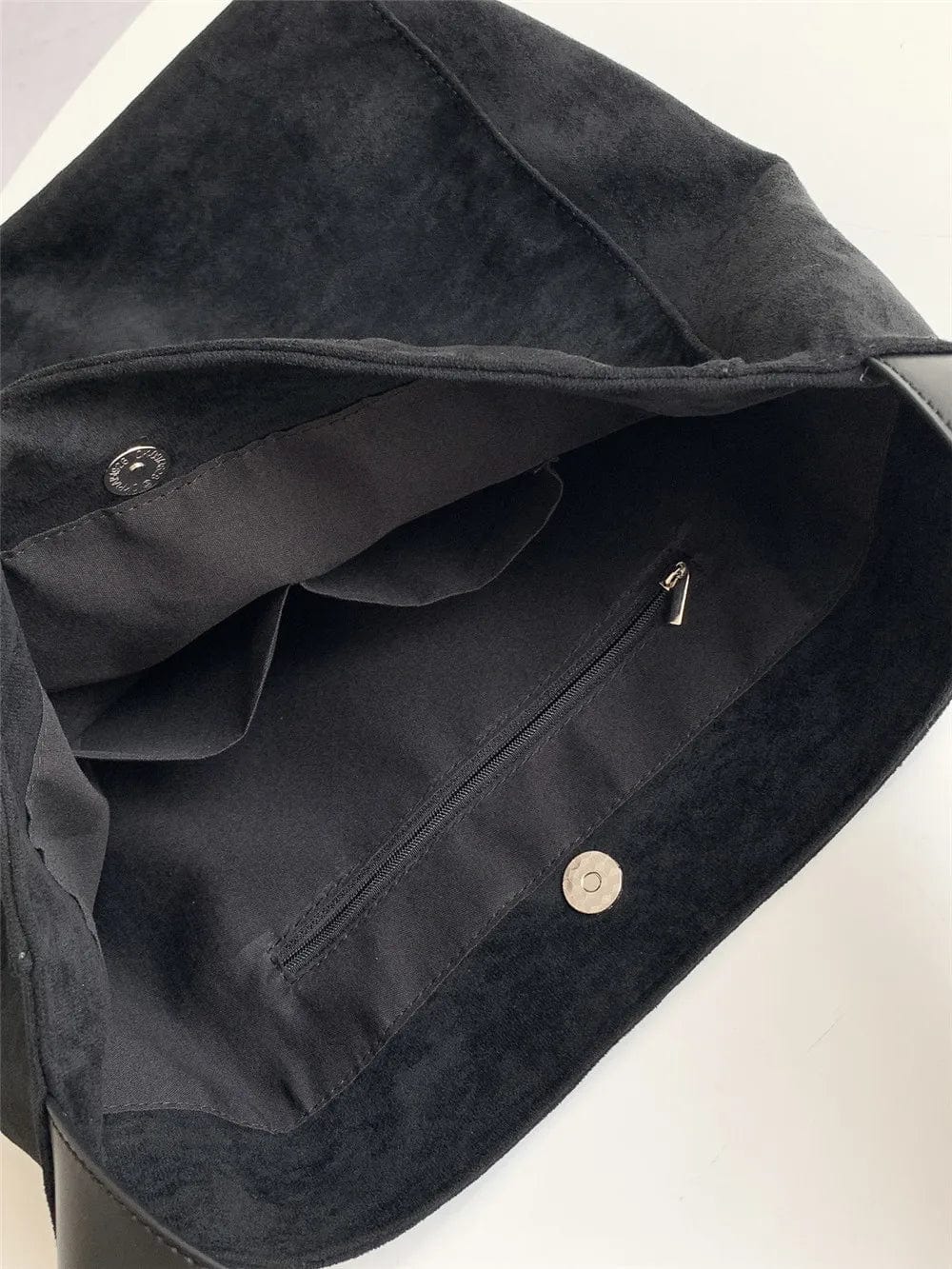 Détail du fermoir doré sur un sac cabas noir en faux daim, ajoutant une touche d'élégance.