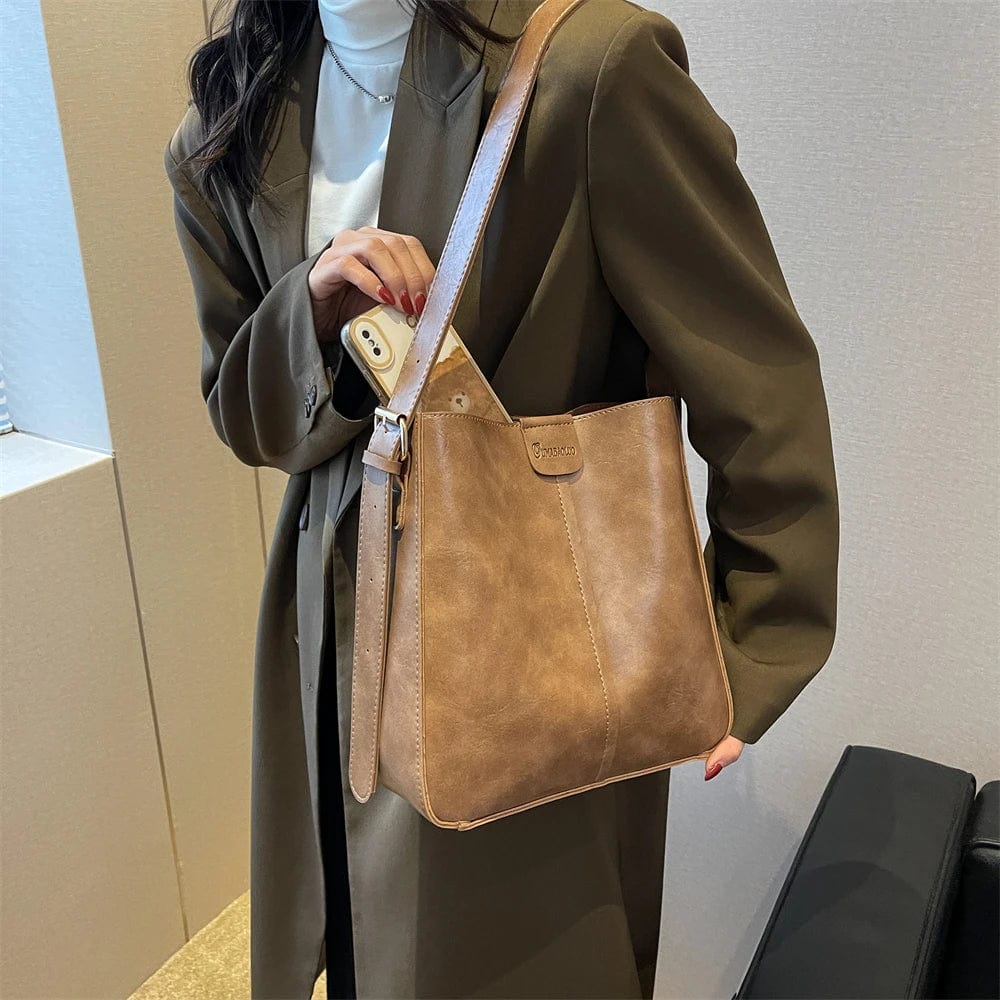 Sac cabas noir en cuir vegan, avec bandoulière robuste, parfait pour un look professionnel ou décontracté.