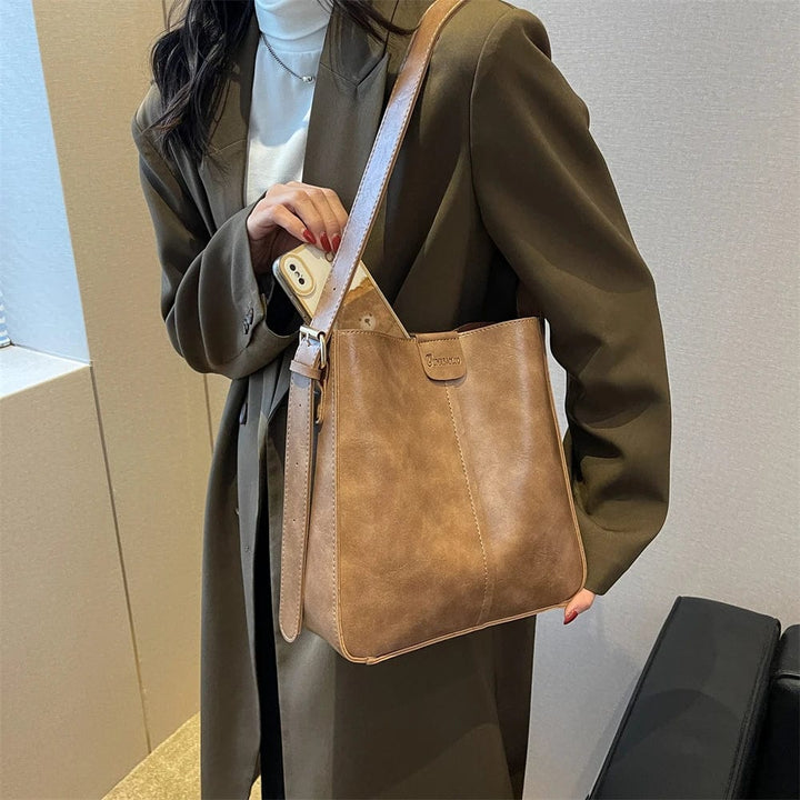 Sac cabas noir en cuir vegan, avec bandoulière robuste, parfait pour un look professionnel ou décontracté.