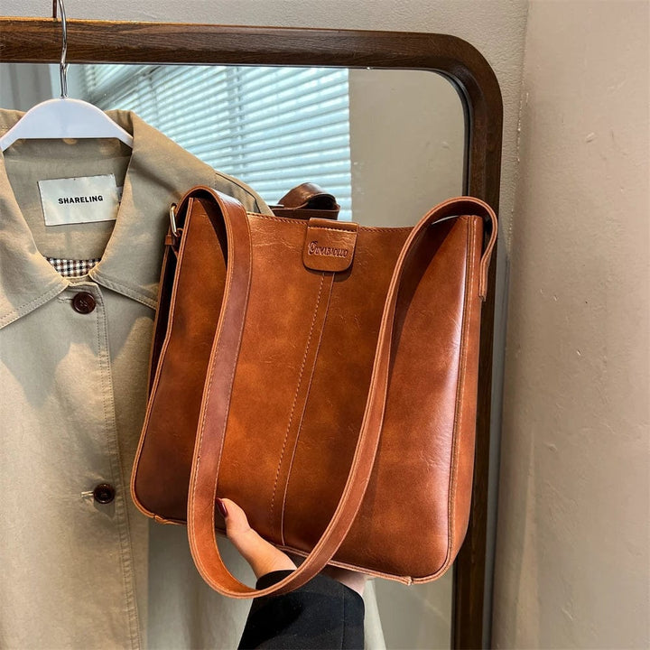 Gros plan sur la texture du cuir vegan du sac fourre-tout femme, avec coutures apparentes et bandoulière.