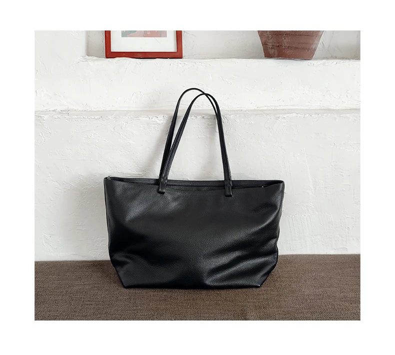 Détail du cuir grainé d'un sac cabas noir pour femme, soulignant la qualité spureuse et élégante.