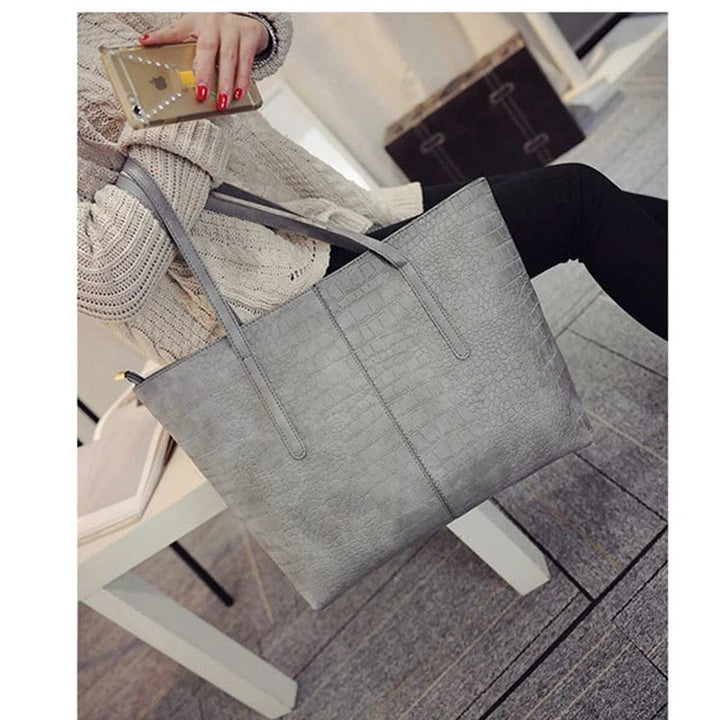 Gros plan sur la texture du cuir vegan noir motif alligator du sac cabas tendance