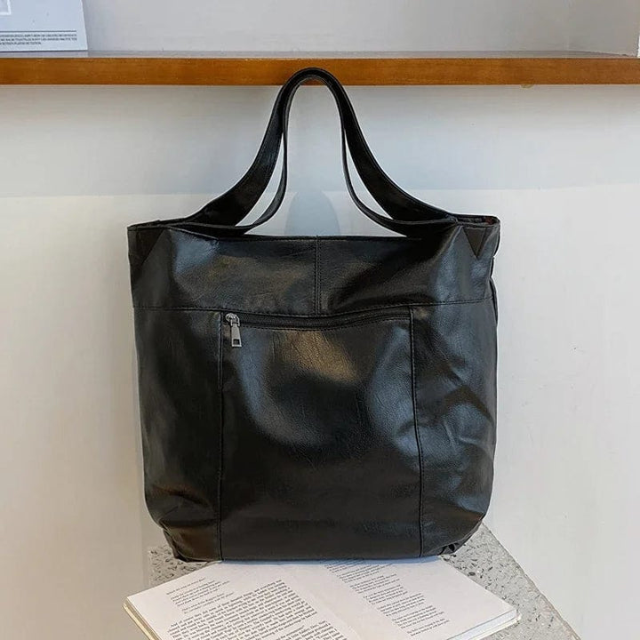 Femme portant le sac cabas en cuir vegan noir à l'épaule, look urbain éthique