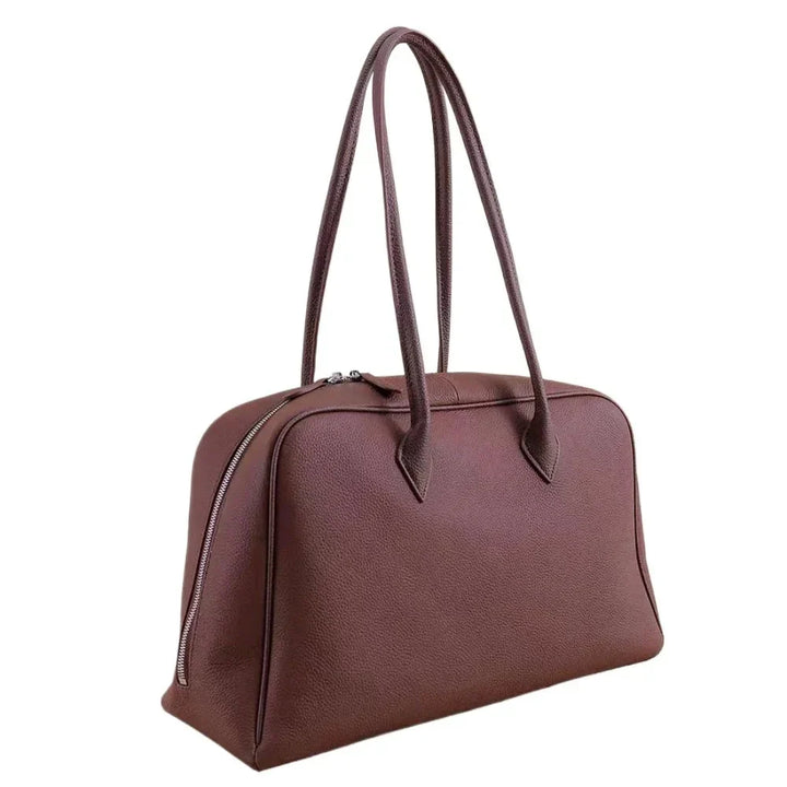 Femme portant un grand sac à main cabas Sanza en cuir grainé sur l'épaule, accessoire de mode élégant.