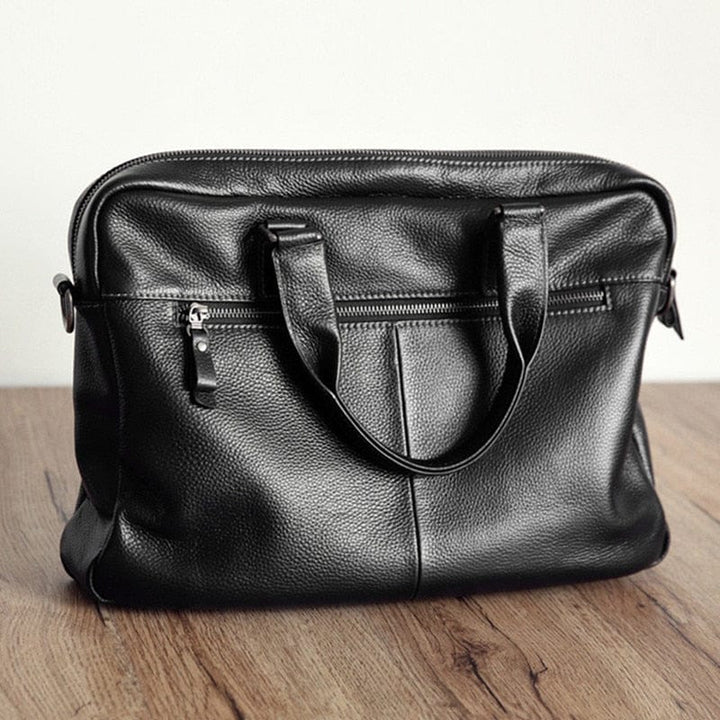 Sac professionnel homme Noam en cuir véritable noir, avec poignée supérieure et bandoulière amovible.