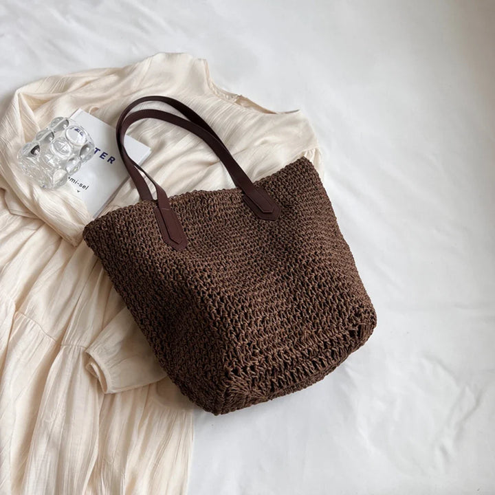 Sac de plage en paille naturelle porté par une femme, accessoire léger pour un look estival.