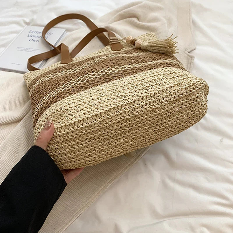 Sac de plage fourre-tout en paille naturelle tressée beige, détails similicuir marron, style bohème.