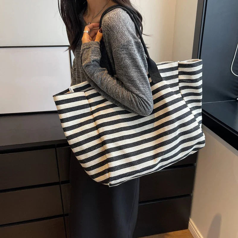 Grand cabas de plage en toile rayée marinière noire et blanche, accessoire de mode estival pour femme.