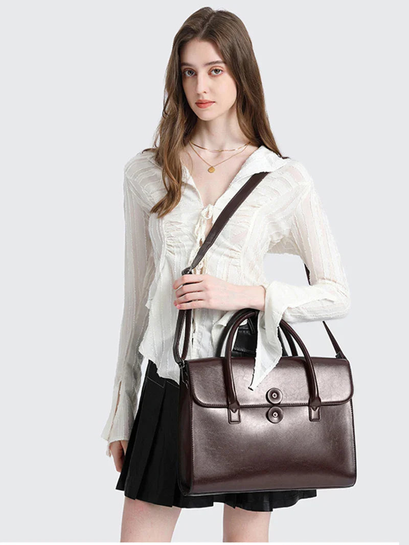 Femme portant le sac de travail Antonella en cuir marron en bandoulière, style professionnel chic.