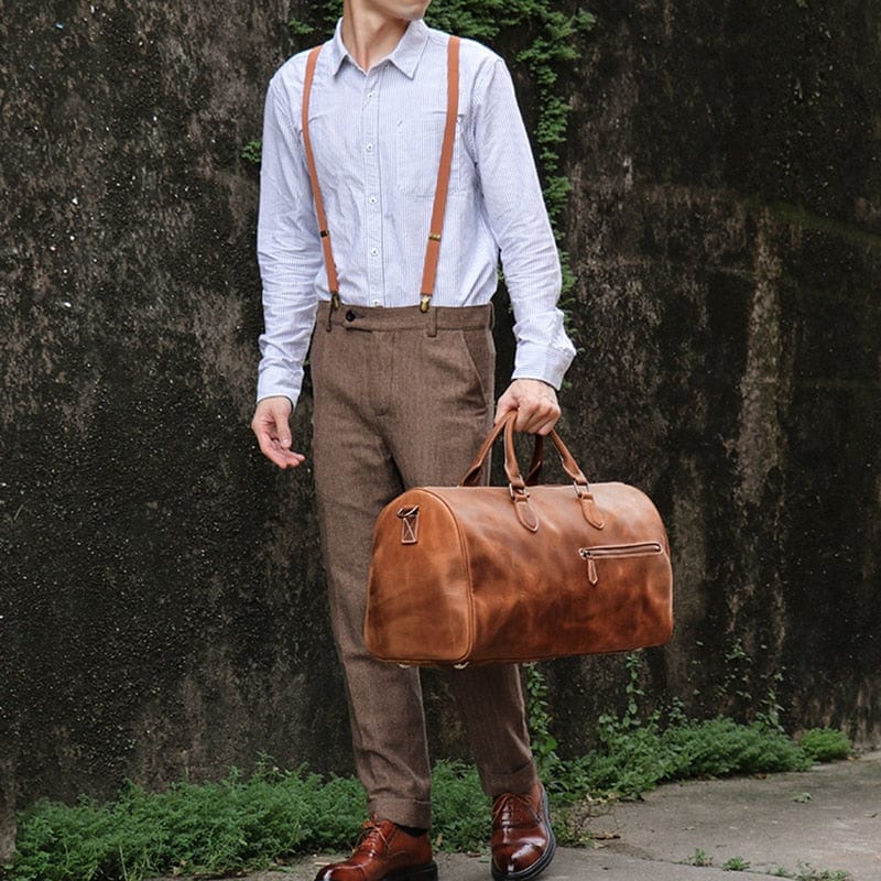 Vue latérale d'un sac de voyage homme en cuir marron, montrant sa forme et sa robustesse