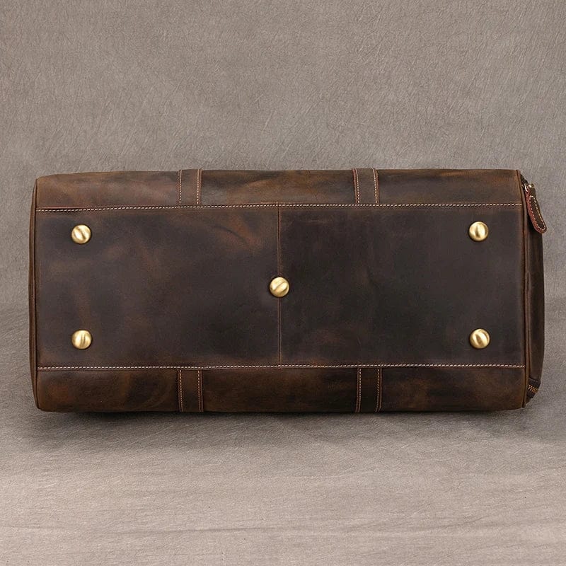 Sac voyage homme en cuir noir posé sur un banc, reflétant luxe et préparation pour un weekend évasion.