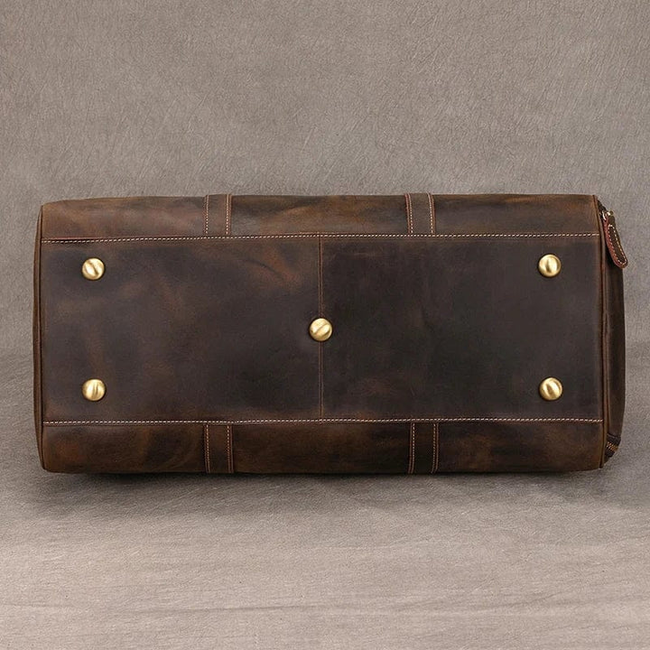 Sac voyage homme en cuir noir posé sur un banc, reflétant luxe et préparation pour un weekend évasion.