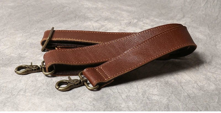 Sac de voyage homme en cuir marron, posé sur une valise, prêt pour le départ, accessoire indispensable