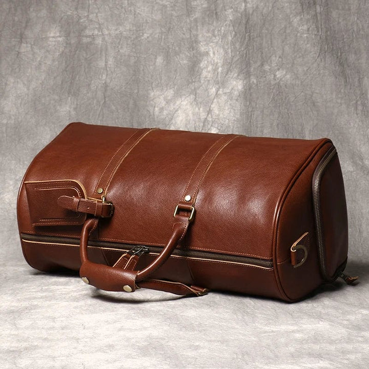 Détail du cuir véritable sur sac de voyage homme, texture et coutures soignées, couleur marron