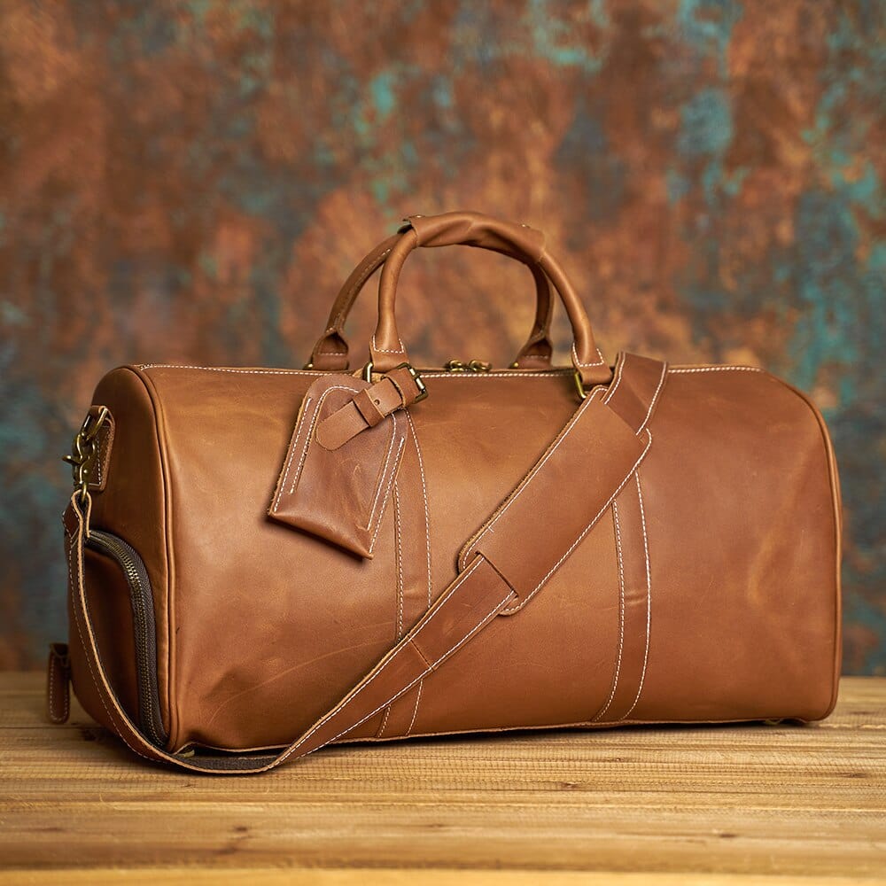Sac de voyage en cuir pour homme porté à l'épaule, idéal pour escapade week-end, style baroudeur chic
