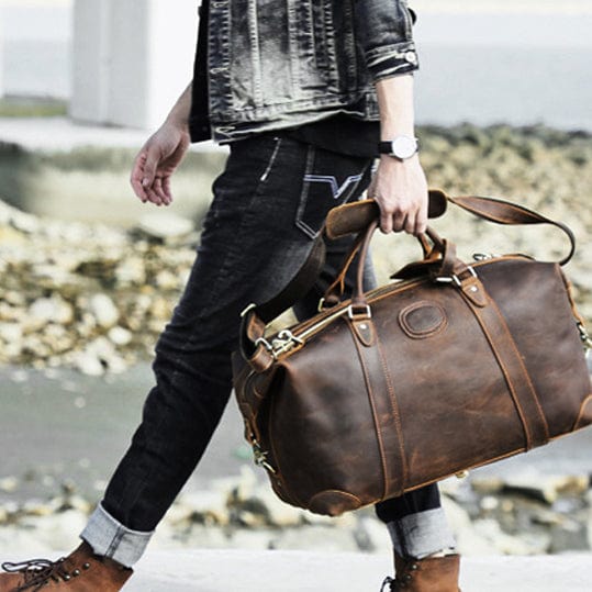 Design classique du sac de voyage homme en cuir véritable, avec poignées renforcées et fermeture éclair.