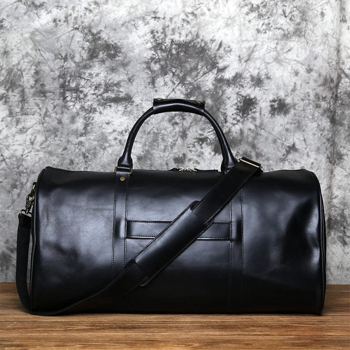 Grand sac de voyage en cuir noir, robuste et chic, parfait pour les bagages cabine
