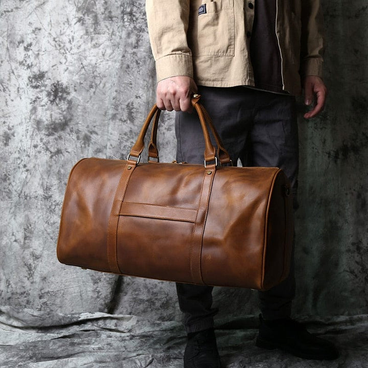 Sac de voyage élégant pour homme, posé sur une valise, couleur marron foncé