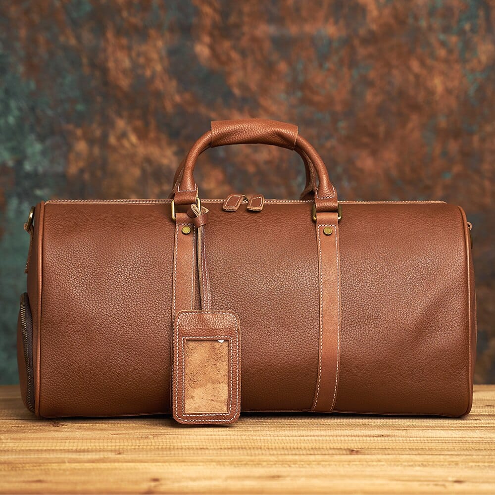 Grand sac week-end en cuir marron clair, avec bandoulière amovible, pour voyage et accessoire homme.