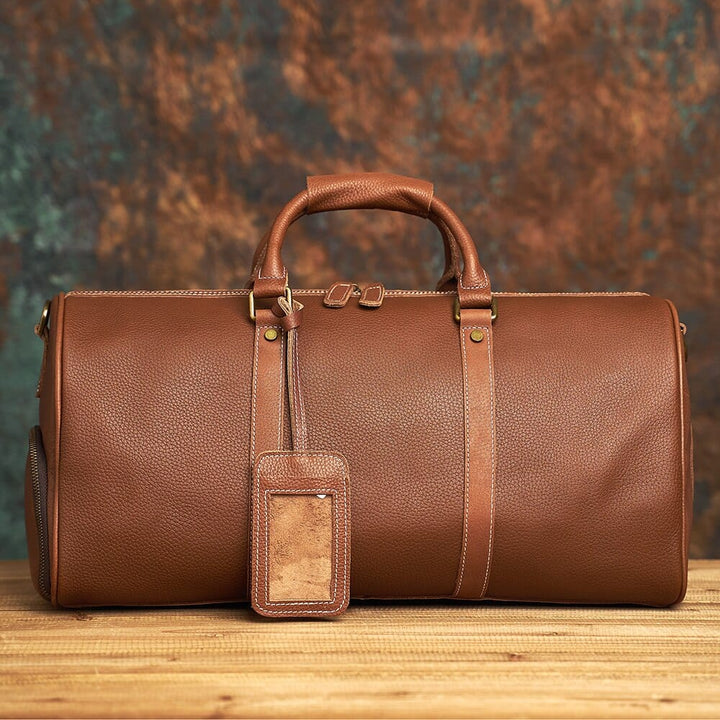 Grand sac week-end en cuir marron clair, avec bandoulière amovible, pour voyage et accessoire homme.