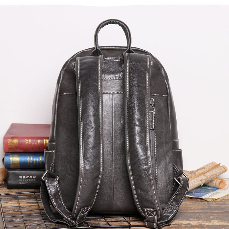 Ouverture d'un sac à dos en cuir noir fonctionnel, révélant son intérieur spacieux pour homme