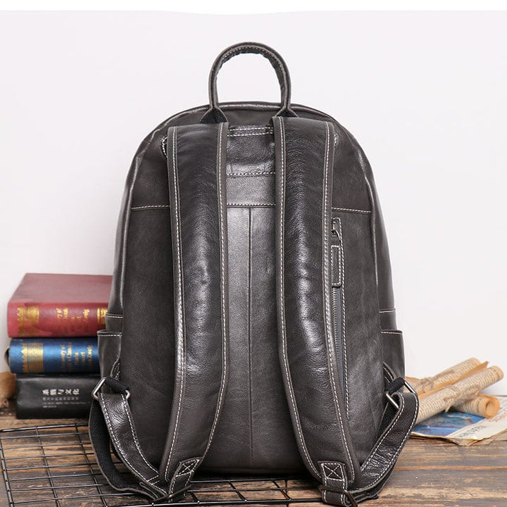 Ouverture d'un sac à dos en cuir noir fonctionnel, révélant son intérieur spacieux pour homme