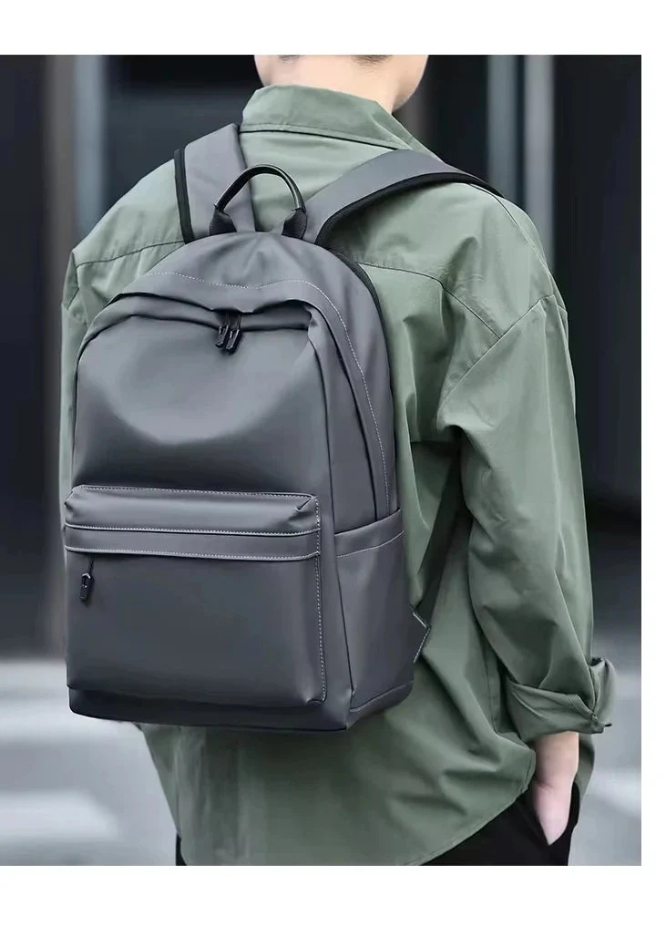 Sac à dos élégant pour homme, gris foncé, avec poche latérale et compartiment dédié pour PC, usage quotidien.