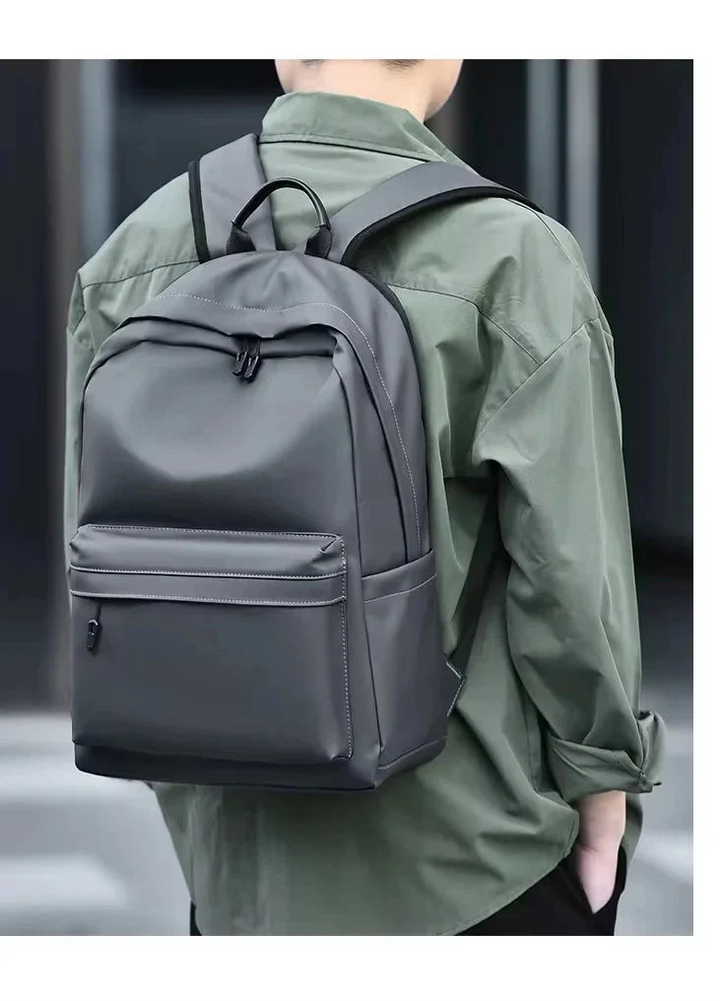 Sac à dos élégant pour homme, gris foncé, avec poche latérale et compartiment dédié pour PC, usage quotidien.