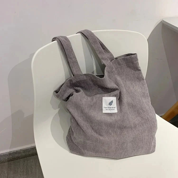 Gros plan sur la texture du sac fourre-tout femme en velours côtelé, élégant et stylé.
