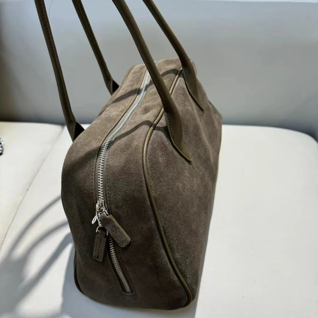Sac en daim bordeaux pour femme, porté épaule, style fourre-tout, ajoutant une touche de couleur à la tenue.