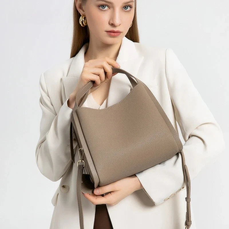 Gros plan sur la texture du cuir grainé du sac à main Astride, détail du fermoir doré