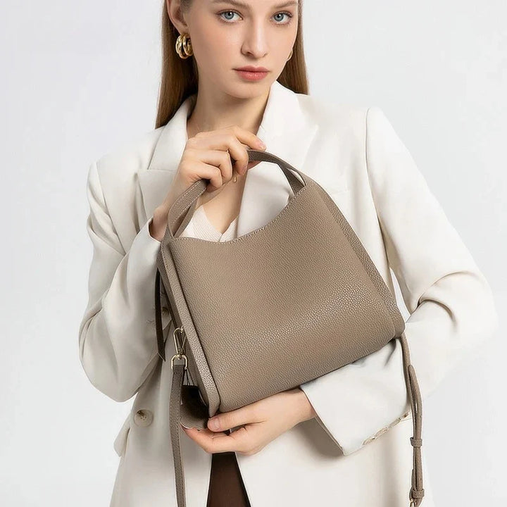 Gros plan sur la texture du cuir grainé du sac à main Astride, détail du fermoir doré