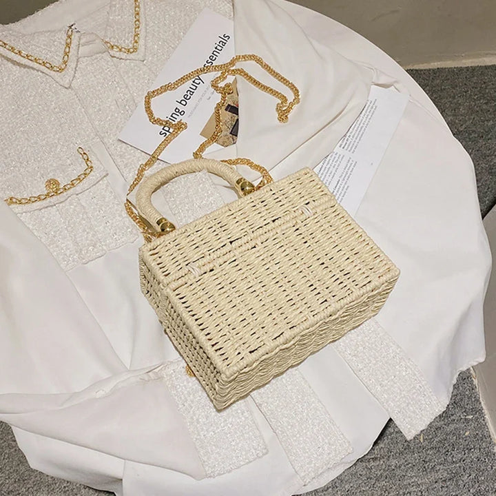 Sac bandoulière carré en paille artisanale beige, idéal pour un look d'été vintage.