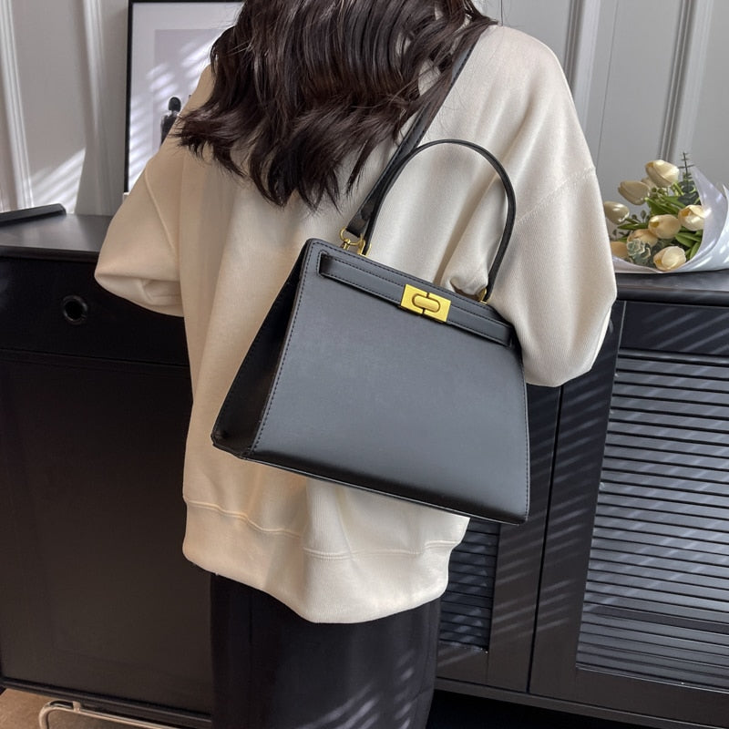 Sac femme noir en cuir synthétique, design carré moderne avec poches et fermeture éclair.