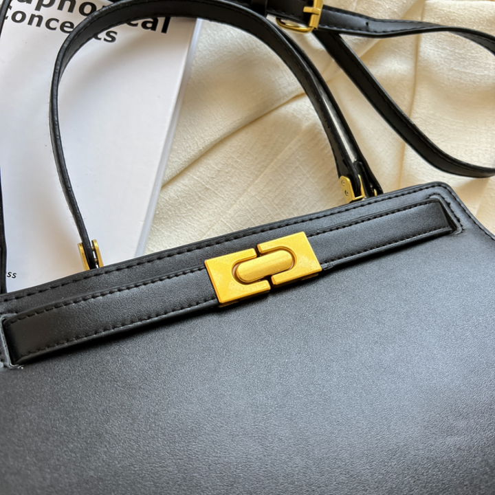 Sac noir chic en cuir synthétique, forme carrée, idéal pour compléter une tenue élégante.