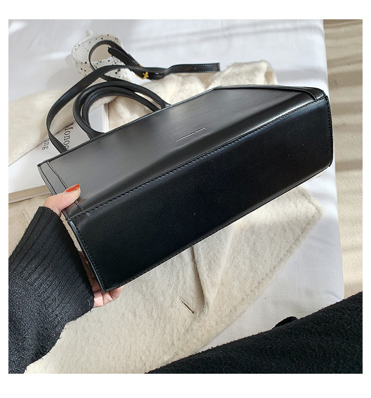 Sac à main femme noir chic, avec bandoulière amovible, offrant un look moderne et fonctionnel pour le bureau.