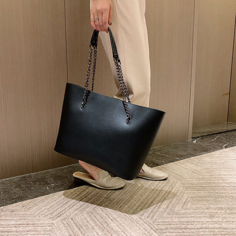 Grand sac noir en cuir synthétique pour femme, avec bandoulière ajustable, parfait accessoire élégant.
