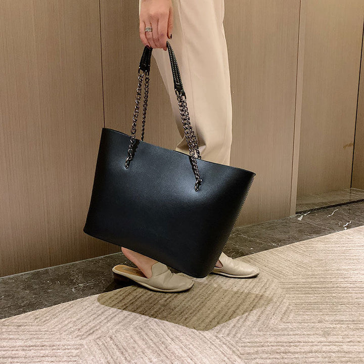 Grand sac noir en cuir synthétique pour femme, avec bandoulière ajustable, parfait accessoire élégant.