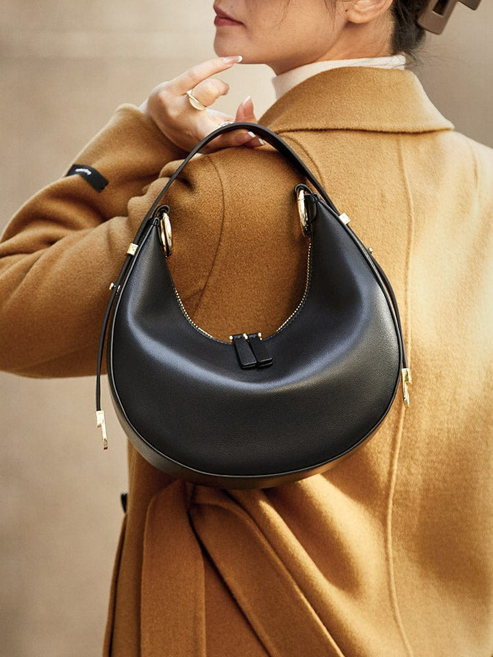 Composition de trois sacs à main demi-lune en cuir (noir, marron, rouge), montrant la gamme de couleurs disponibles.