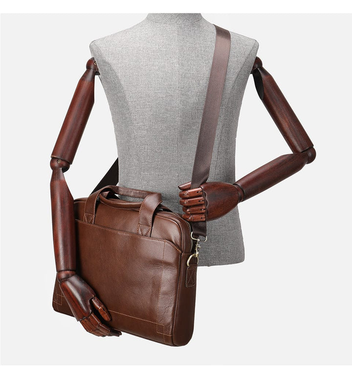 Sac à main homme posé sur un bureau avec un ordinateur portable, prêt pour le travail