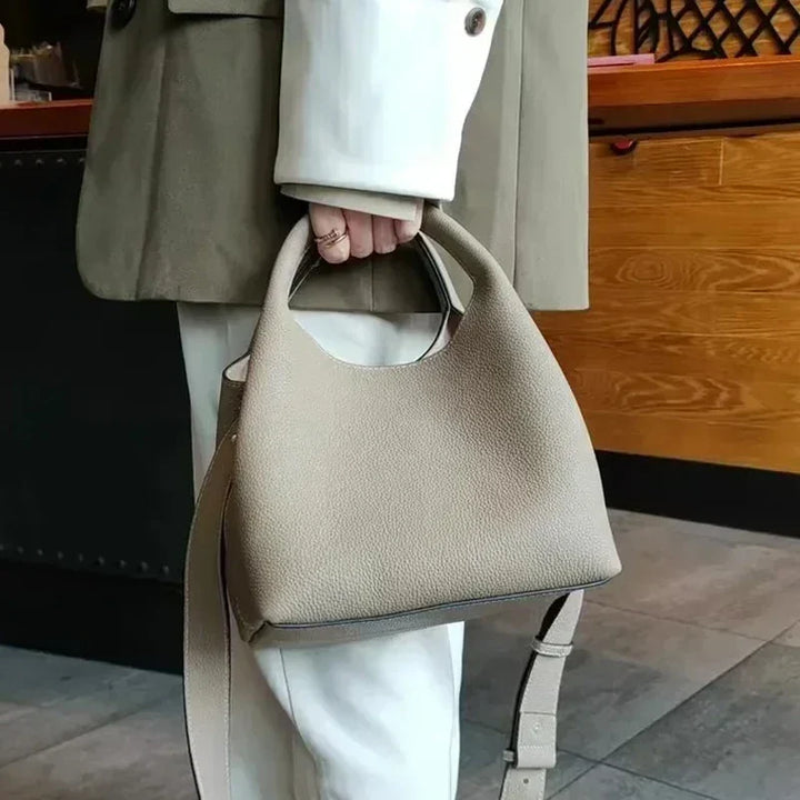Sac à main femme en cuir de luxe moderne noir, style seau, anses, bandoulière amovible, doublure rouge.