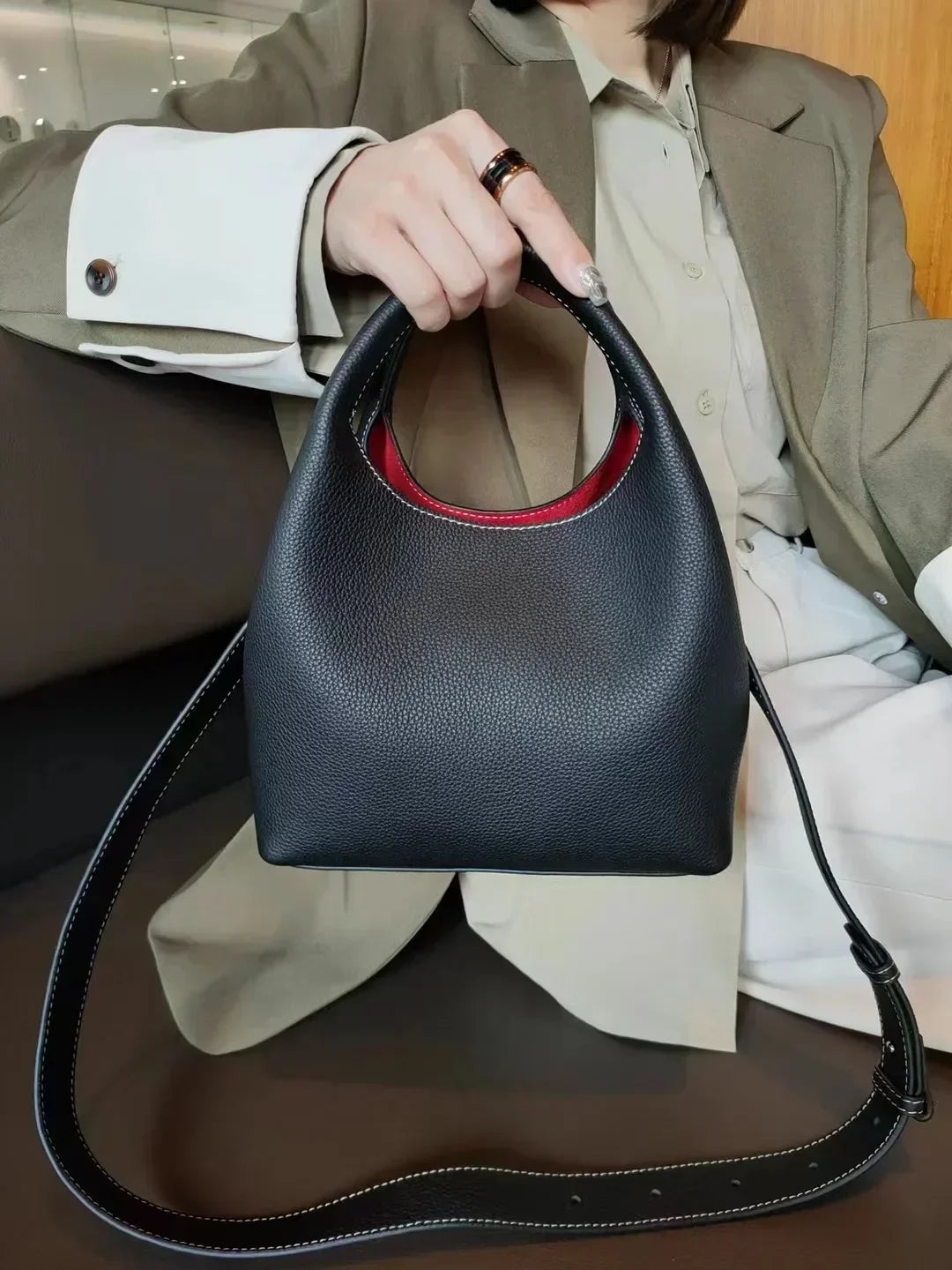 Détail du fermoir doré sur sac à main femme en cuir de luxe noir, gravure, qualité des finitions.