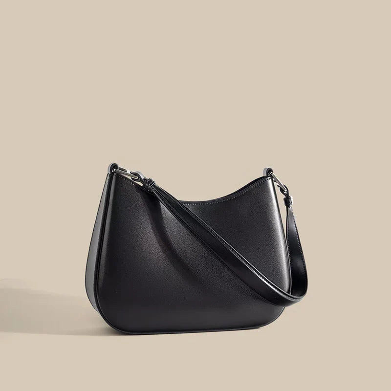 Sac bandoulière femme en cuir noir, avec finitions métalliques dorées, accessoire mode de luxe.