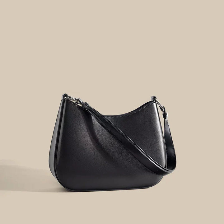 Sac bandoulière femme en cuir noir, avec finitions métalliques dorées, accessoire mode de luxe.