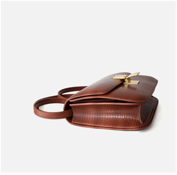 Femme portant un sac à main motif croco élégant, affichant un style mode à l'épaule.
