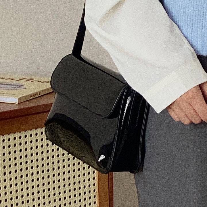 Photo gros plan sac à main femme noir brillant, texture vinyle, style élégant et polyvalent.
